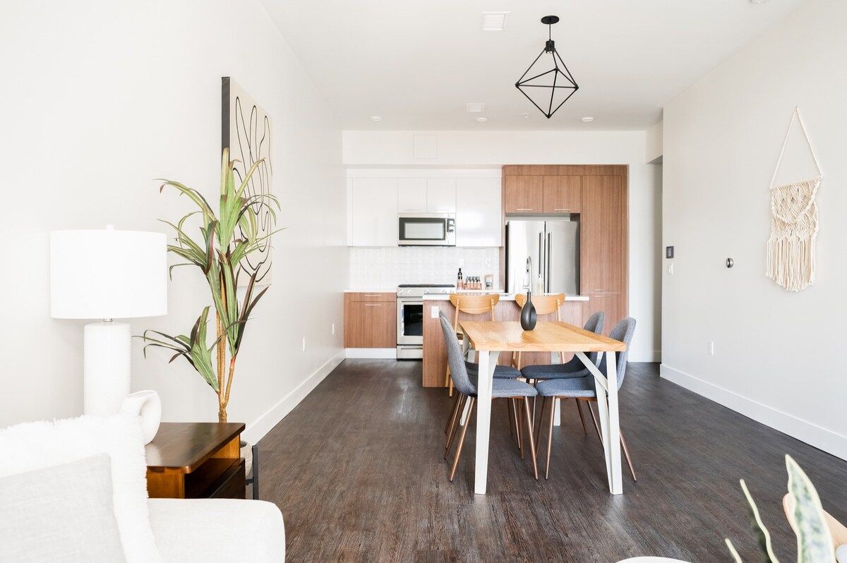 A modern kitchen with white cabinets, a microwave, and a wooden countertop.