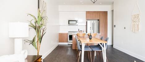 A modern kitchen with white cabinets, a microwave, and a wooden countertop.