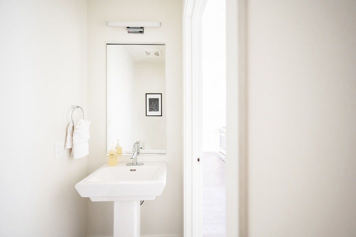 A white bathroom with a sink, mirror, and towel rack.