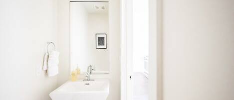 A white bathroom with a sink, mirror, and towel rack.