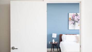 Ett hotellrum med en säng, ett sängbord med en lampa och en tavla som hänger på väggen.