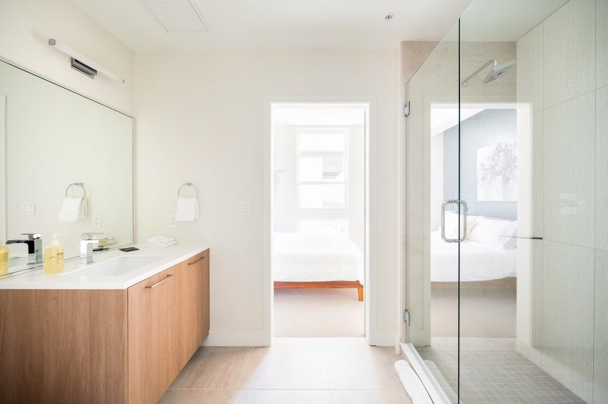 Une salle de bain moderne avec une douche à parois de verre, un meuble-lavabo en bois et un grand miroir.