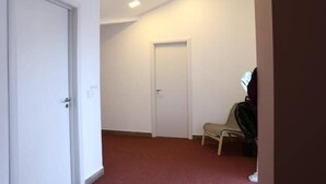 En hall med en stängd dörr, en bänk och en krukväxt.