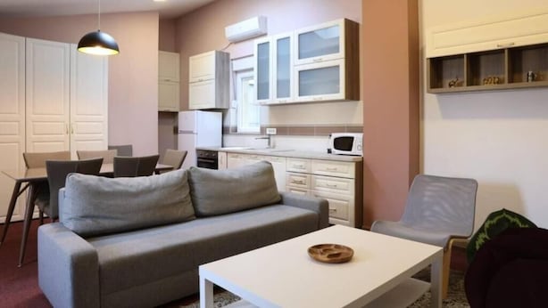 Ett kompakt bostadsutrymme med ett litet kök, en soffa, ett matbord och en stol.