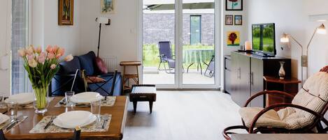 A dining area with a table set for two, a sofa, and a TV in the background.