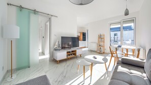 A modern living room with a TV, sofa, and dining area. - Apartamenty Sun & Snow Zielona Zatoka (Ustka)