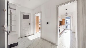 A hallway with white doors leading to a kitchen and a bedroom.