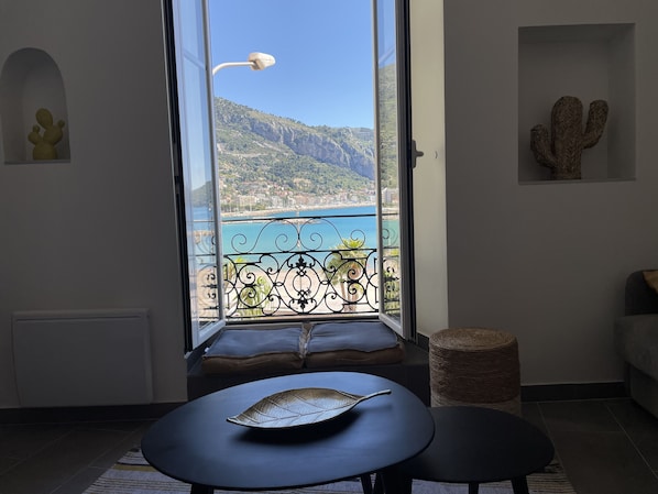 A balcony with a view of a coastal town and mountains.