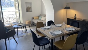 Een eetruimte met een tafel voor vier personen, een bank en uitzicht op zee.