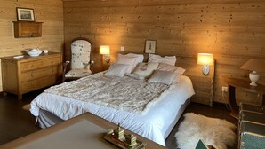 A wooden-paneled bedroom with a large bed, two bedside lamps, a wooden dresser, and a chair. - Contemporary chalet, panoramic view (ORMONT DESSOUS)
