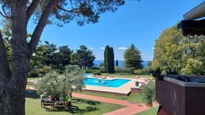A swimming pool with a clear view of the sea, surrounded by trees and a well-maintained lawn. - Regarda - Blue View 2 with lake view, 2 bedrooms, pool (Bardolino)
