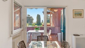 A room with a sliding glass door leading to an outdoor patio, a table with chairs, and a radiator. - Regarda - Blue View 2 with lake view, 2 bedrooms, pool (Bardolino)