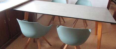 A dining area with a long table and four light blue chairs with wooden legs.