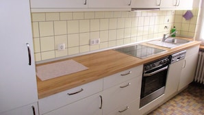 A kitchen with white cabinets, a wooden countertop, a stainless steel sink, and a built-in oven. - Modern apartment on the 1st floor, 3 rooms + dining area, kitchen w. Dishwasher, bathroom (Cuxhaven)