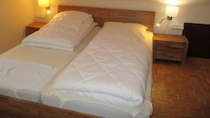 A double bed with white bedding, two bedside tables with lamps, and a wooden headboard. - Modern apartment on the 1st floor, 3 rooms + dining area, kitchen w. Dishwasher, bathroom (Cuxhaven)