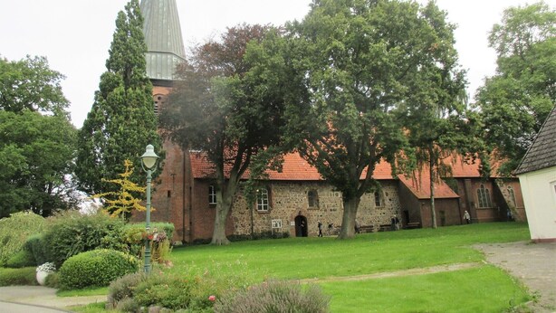 A church with a tall steeple, surrounded by trees and a well-maintained lawn. - Modern apartment on the 1st floor, 3 rooms + dining area, kitchen w. Dishwasher, bathroom (Cuxhaven)