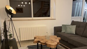 Un salon moderne avec une table basse en bois, un meuble TV noir, un canapé gris et un tapis à rayures.