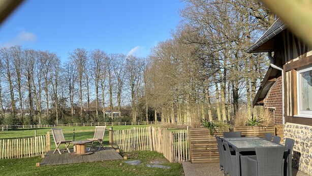 Un espace patio avec une table et des chaises, un petit jardin et une clôture en bois.