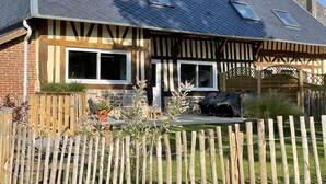 Une maison à deux étages, dotée d’un toit à pignon, de lucarnes et d’une clôture en bois.