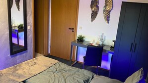 A bedroom with a bed, a desk, and a wardrobe.