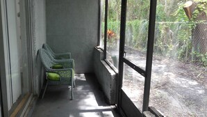 A balcony with a chair, a window, and a view of a garden. - Family-Friendly 2BR Condo Near Universal (Orlando)