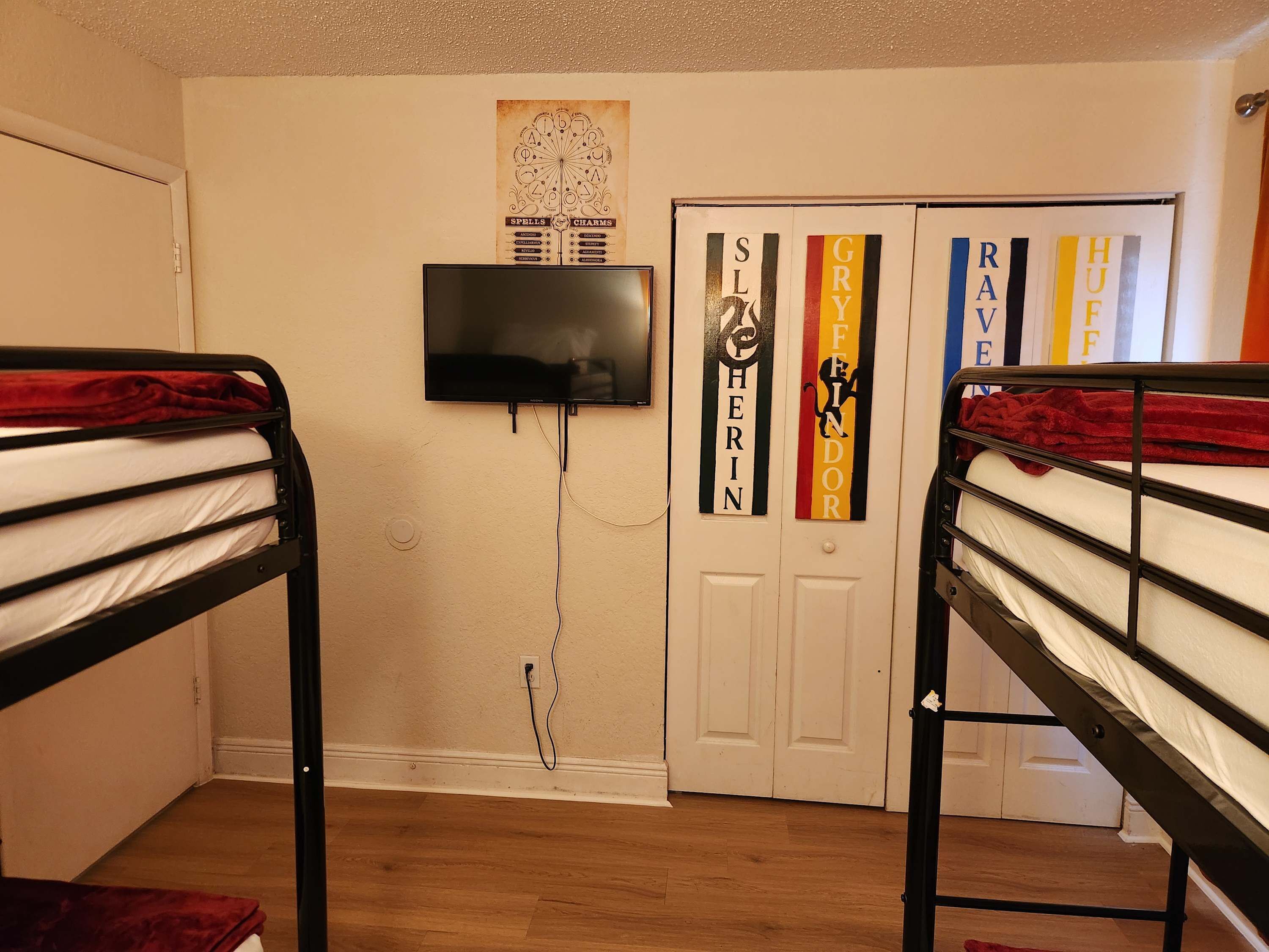 Ein Zimmer mit zwei Etagenbetten, einem an der Wand montierten Fernseher und einer Tür mit dekorativen Verzierungen.