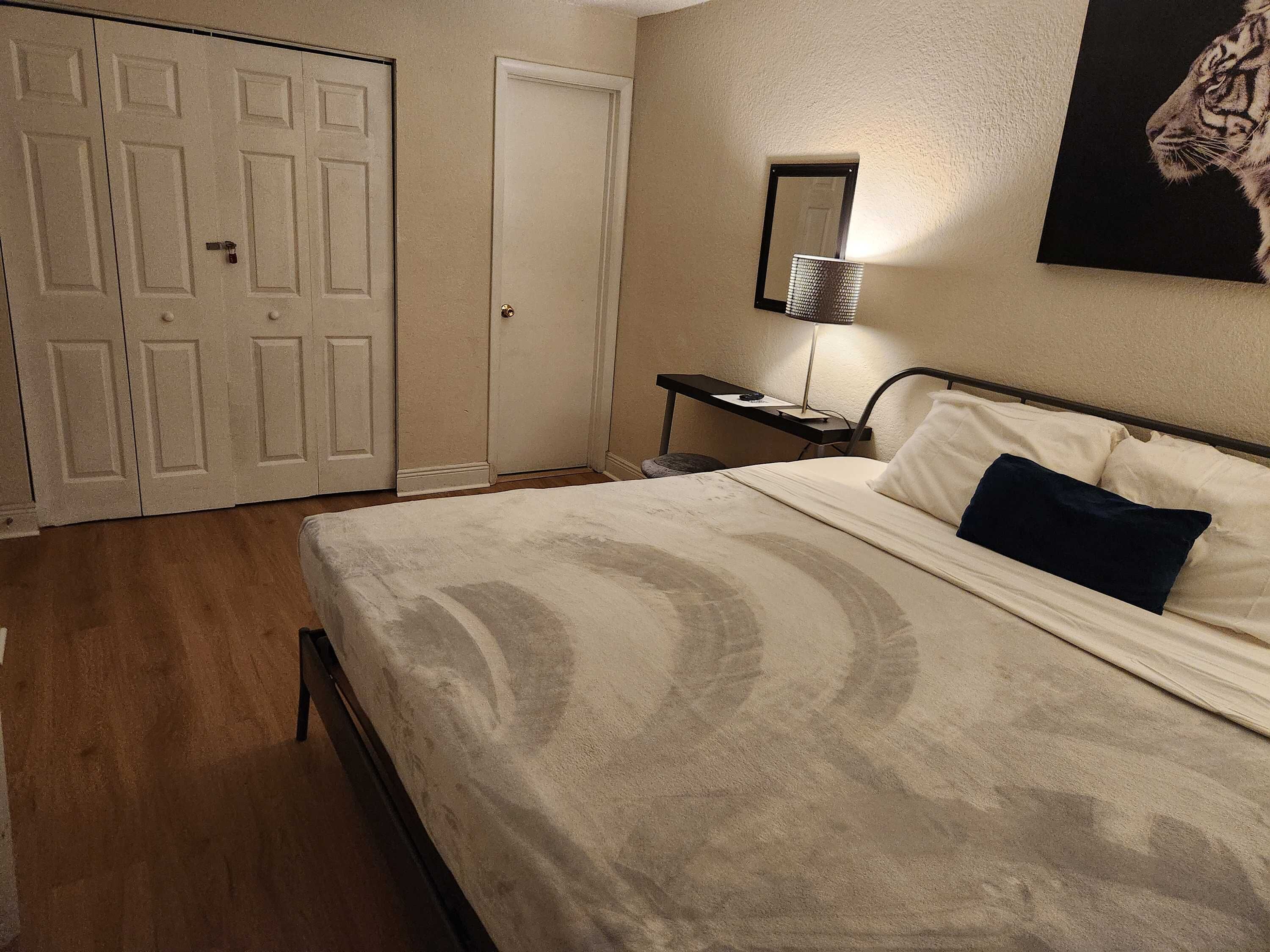 Quarto com cama, escrivaninha, cadeira, porta e espelho na parede.