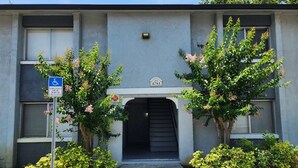 A building with a gated entrance, a disabled parking sign, and a house number sign. - Family-Friendly 2BR Condo Near Universal (Orlando)