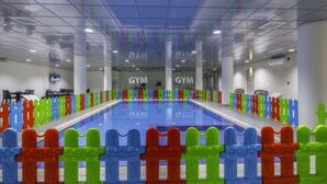 A swimming pool with colorful fences, gym signs, and a tiled floor. - THE ADDRESS PALACE HOTEL & APARTMENT (Dammam)