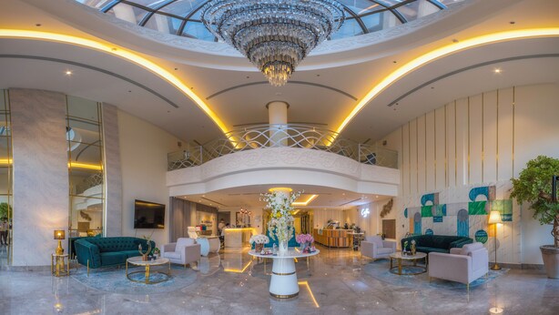 A spacious lobby with a high ceiling, a central chandelier, and a seating area with sofas and tables. - THE ADDRESS PALACE HOTEL & APARTMENT (Dammam)