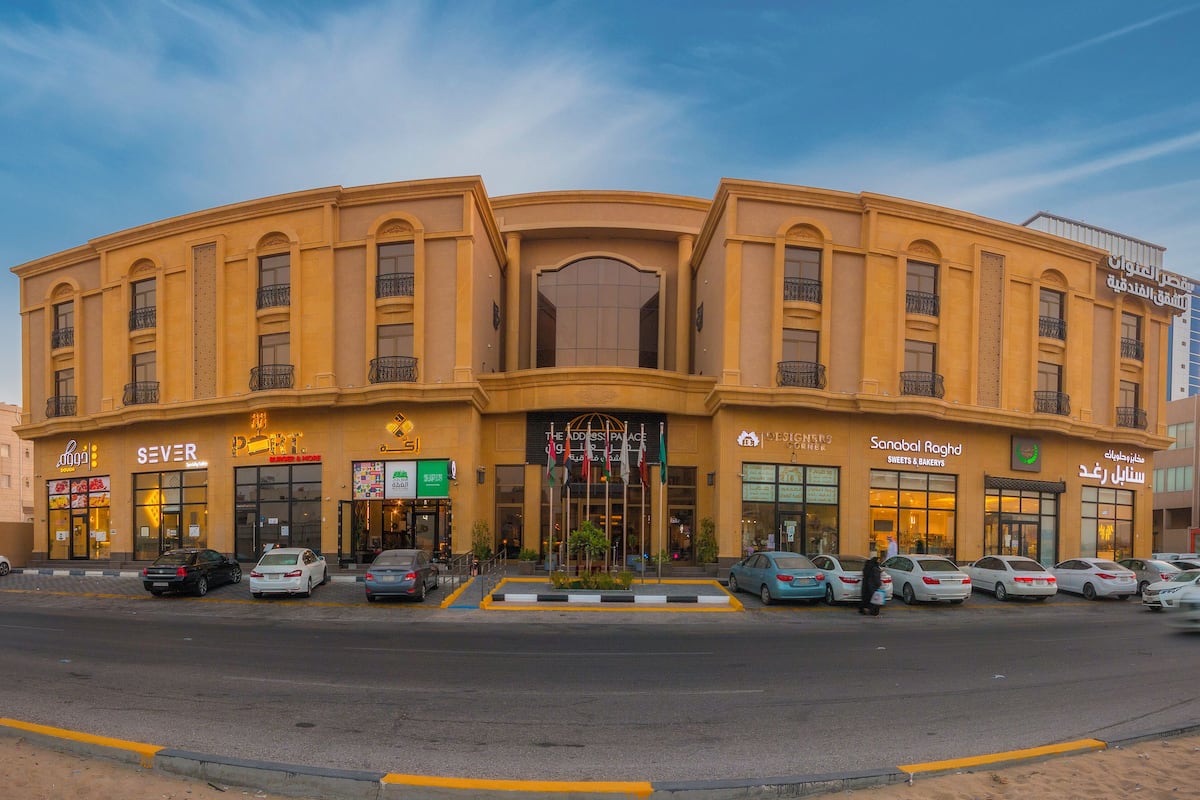 A multi-story building with various shops on the ground floor, including a bakery and a restaurant.