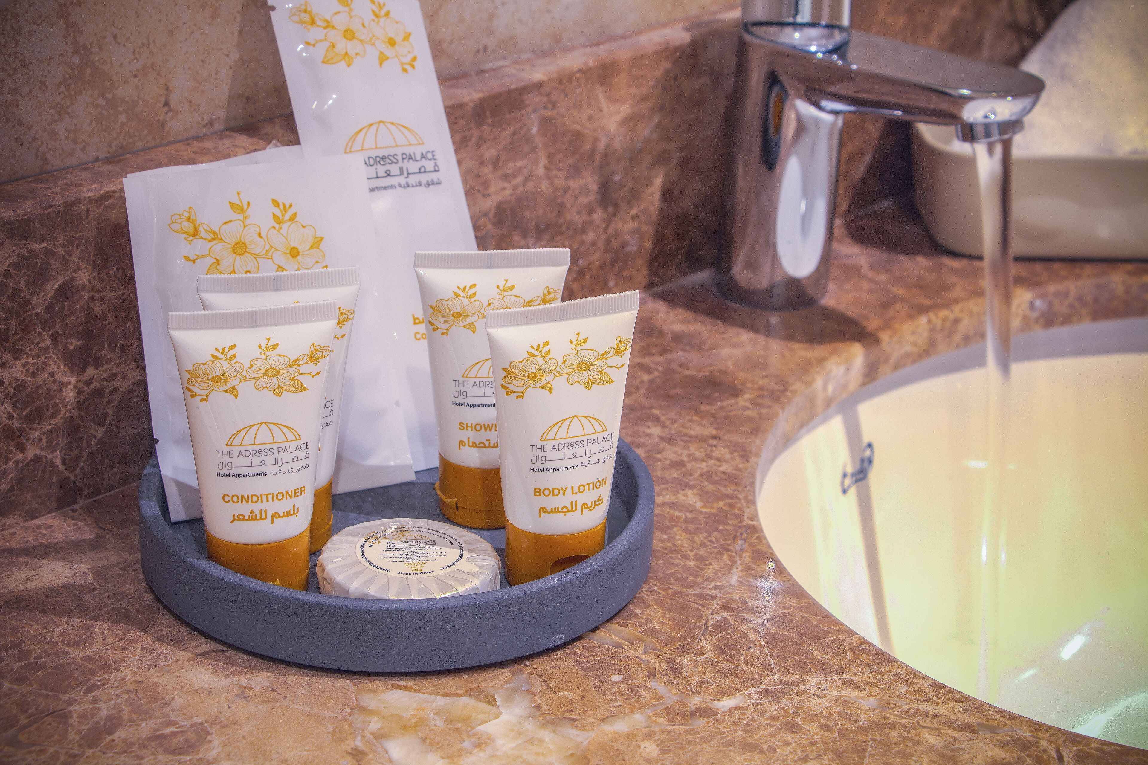A bathroom counter with toiletries including a bottle of conditioner, a tube of body lotion, and a bar of soap.