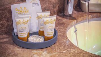 A bathroom counter with toiletries including a bottle of conditioner, a tube of body lotion, and a bar of soap.