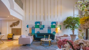 A modern living room with a green sofa, white armchairs, a round coffee table, and a potted plant. - THE ADDRESS PALACE HOTEL & APARTMENT (Dammam)