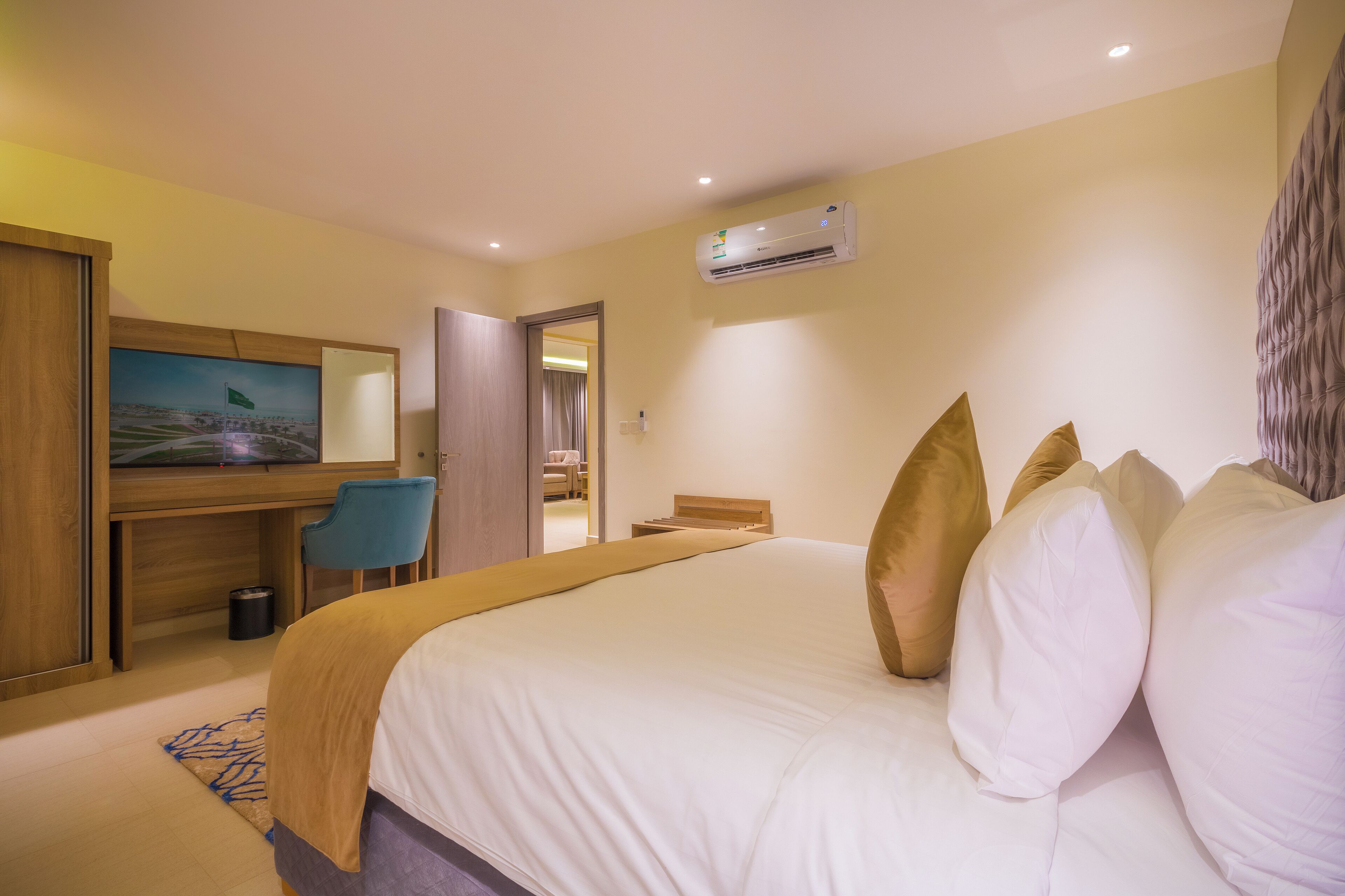 A hotel room with a bed, a desk, a chair, and an air conditioning unit.