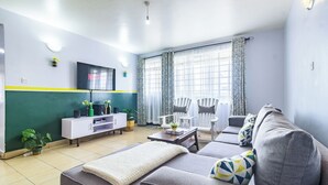 A living room with a sofa, a coffee table, a TV, and a cabinet. - Hirwado Homes - QUIET/Secure/15 Mins to JKIA /SGR (Mlolongo)