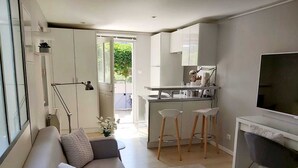 Una sala de estar moderna con un sofá, un televisor y una zona de cocina con taburetes de bar.