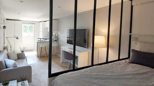 Un dormitorio moderno con una cama grande, un escritorio con televisor y una zona de estar con sofá y sillones.