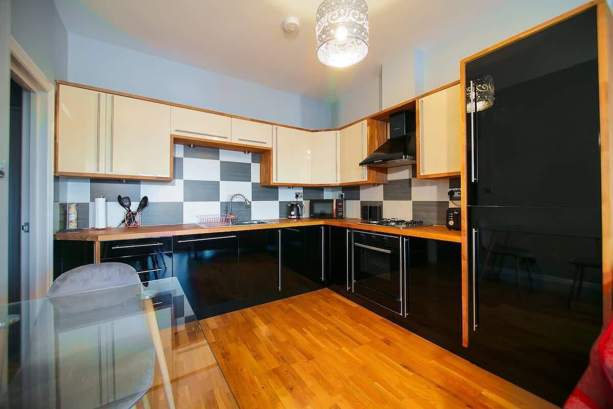 Una cocina moderna con armarios de madera, un refrigerador negro y un protector contra salpicaduras a cuadros.