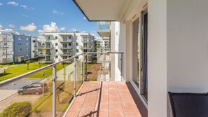 A balcony with a clear view of adjacent apartment buildings, a grassy area, and a parked car. - Prywatne apartamenty w Sun & Snow Porta Mare (Kolobrzeg)