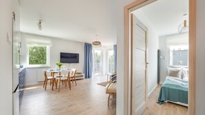 A modern, well-lit room with a dining area, a TV, and a bed. - Prywatne apartamenty w Sun & Snow Porta Mare (Kolobrzeg)