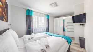 Una habitación de hotel con una cama, cortinas, un televisor y un armario.