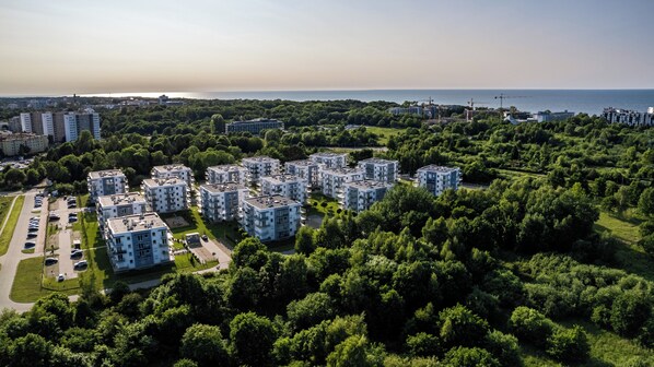 An aerial view of a residential area with modern apartment buildings, a parking lot, and a body of water in the background. - Prywatne apartamenty w Sun & Snow Porta Mare (Kolobrzeg)
