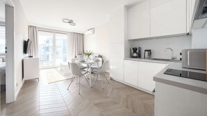 A modern kitchen with white cabinetry, a built-in microwave, and a coffee maker. - Prywatne apartamenty w Sun & Snow Porta Mare (Kolobrzeg)