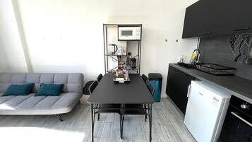 A compact living space with a sofa, dining table, kitchenette, and a small refrigerator.