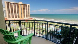 A balcony with a green chair, overlooking a beach with a hotel in the background. - Oceanviews-Steps 2 Beach-Stunning-MultiBalconies-Gated Community-Pool/Hottub (Myrtle Beach)