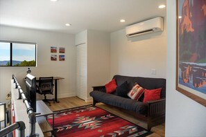 Una sala de estar moderna con un sofá, un escritorio y vistas al exterior.