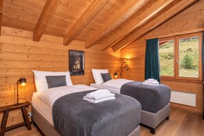 A wooden cabin room with two beds, a poster on the wall, and a window with curtains.
