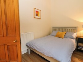 Un dormitorio con cama, una puerta de madera, un radiador y un cuadro enmarcado en la pared.