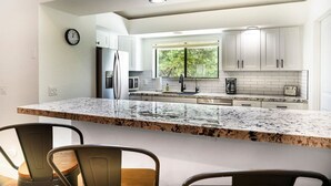 A modern kitchen with white cabinets, a granite countertop, and a built-in oven. - Modern Zen Luxury · With Views · Centrally Located (Sedona)
